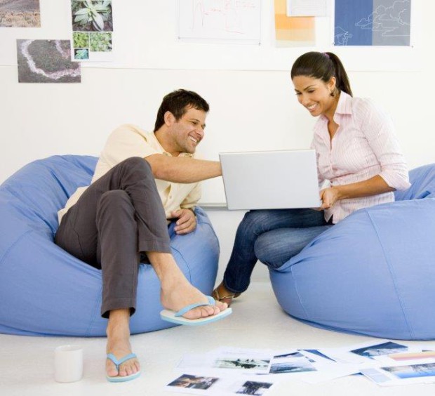 Man and Woman Laughing, Looking at a Laptop Whilst sat in Beanbags