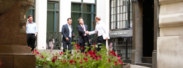 Two Businessmen Shaking Hands Outside By a Railing