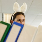 Young woman wearing bunny ears in office, folders in foreground