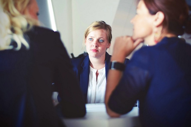 A Business Woman With a Strained Face Looking at two Other Business Women