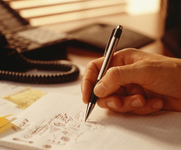 A Person Drawing in Their Notepad (Close-up)