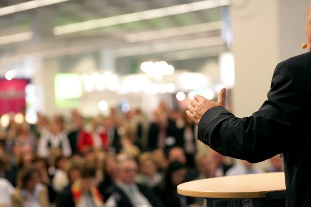 A Business Man Giving a Speech To a Large Crowd
