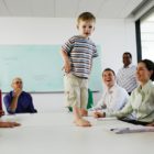 Boy (2-4) standing on table in business meeting